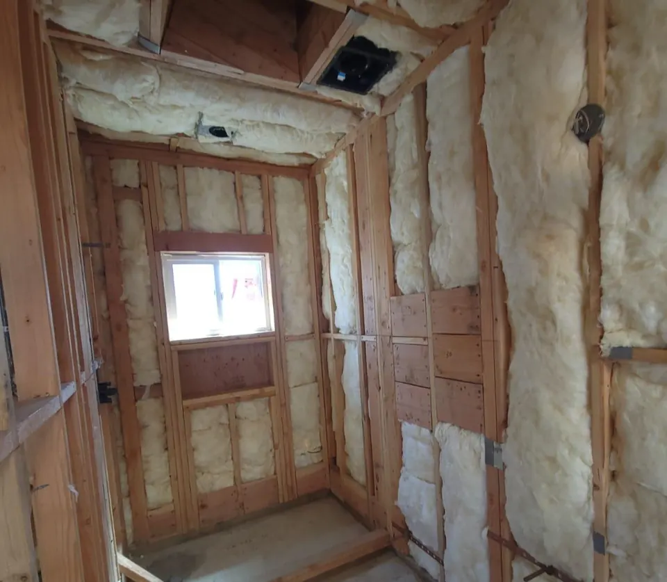 The ADU bathroom during construction with exposed framing, insulation and rough plumbing