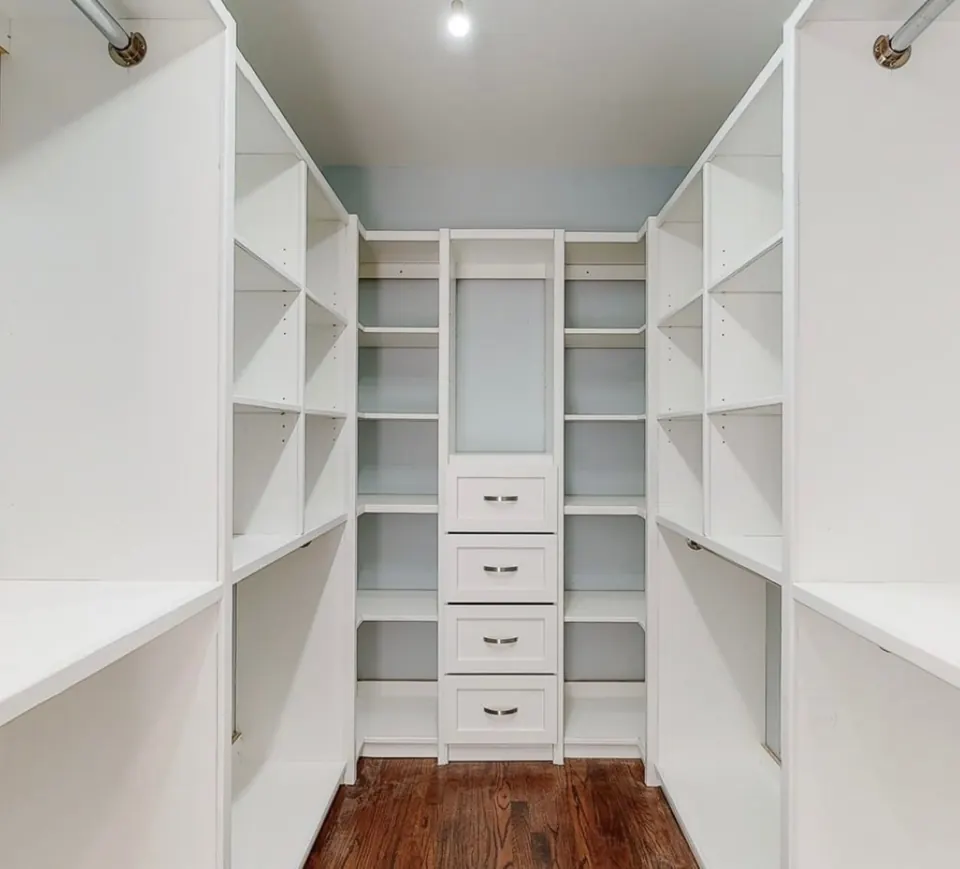 Walk-in closet rebuilt with custom white shelving, a bank of drawers and double hanging space