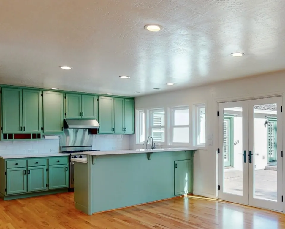 The kitchen before the remodel, with green-painted cabinets and an older layout