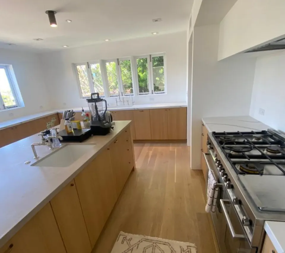 Remodeled kitchen with light-oak cabinetry, a long counter run and a professional-style range under a row of windows
