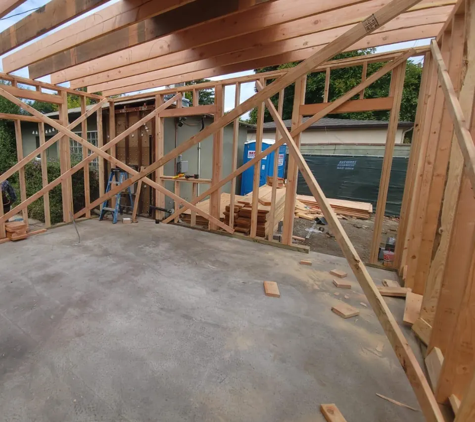 The same space during framing, with open walls and roof framing above the future kitchen