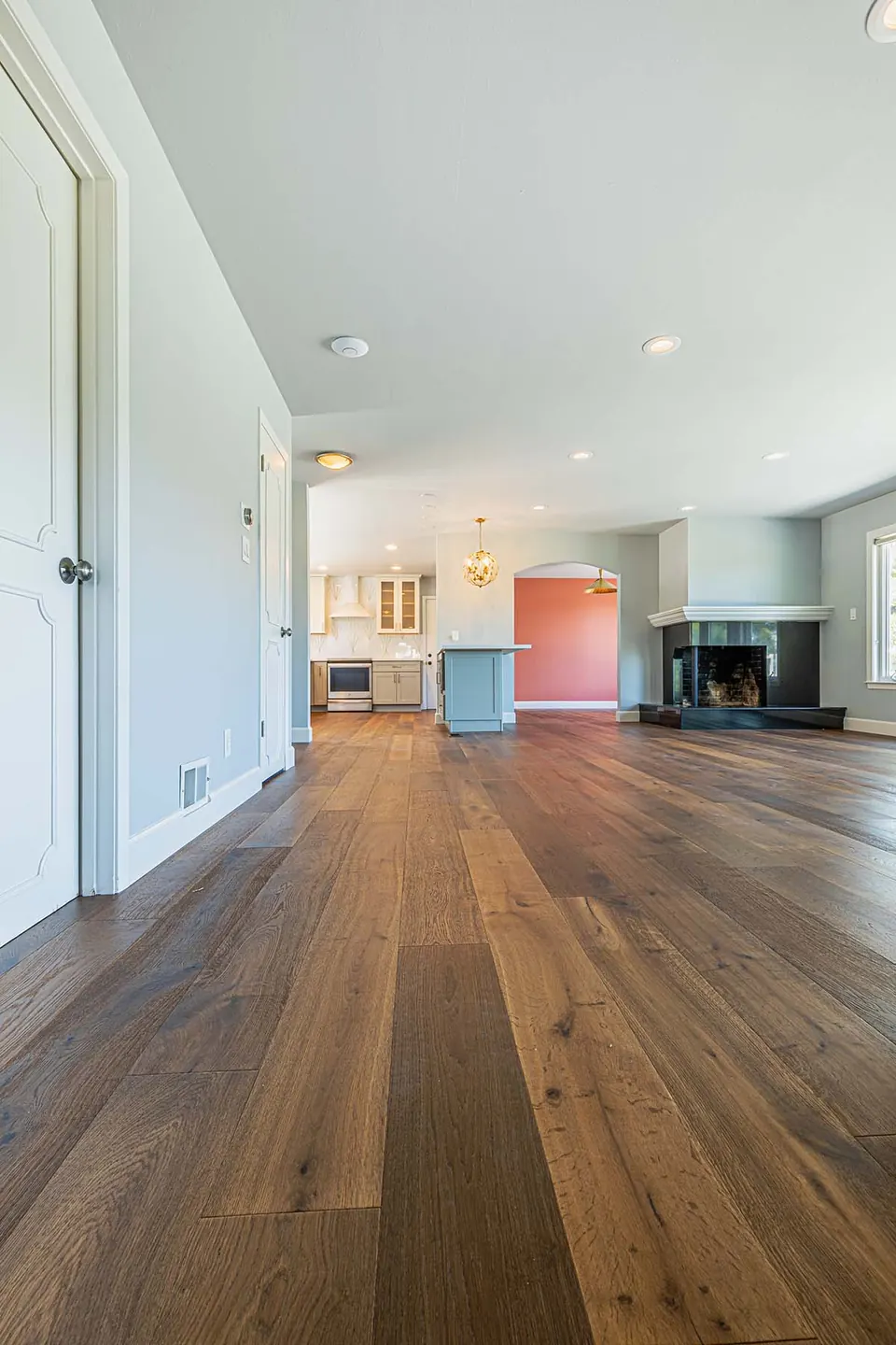 Interior renovation with wide-plank oak floors running from the entry through to a living room with a corner fireplace