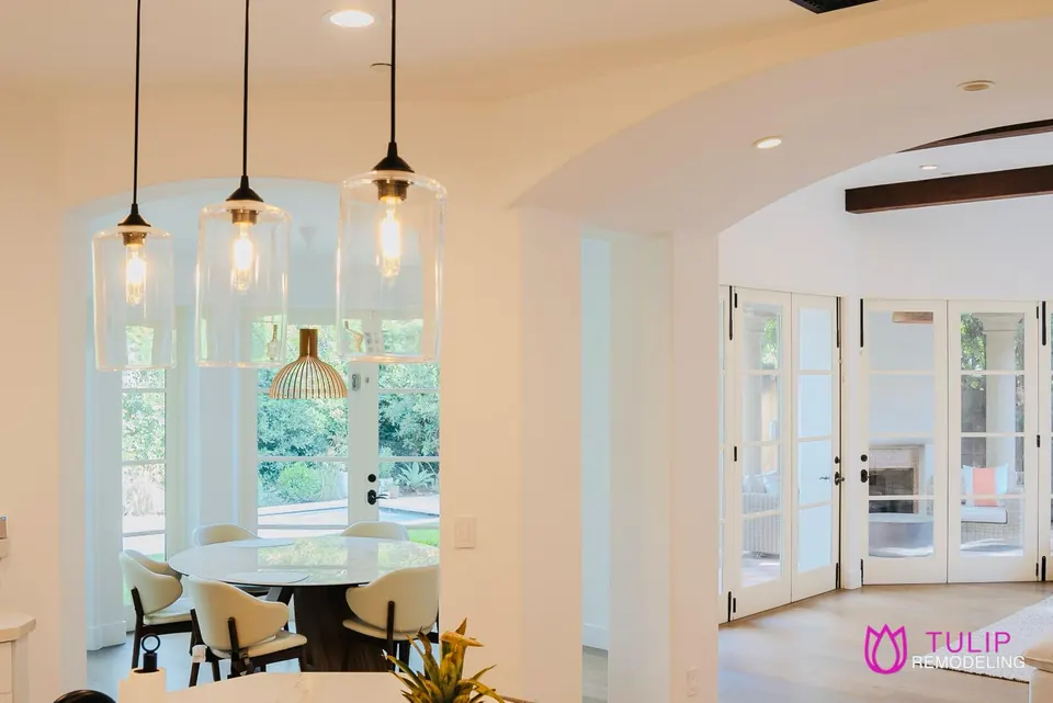 Breakfast nook with three clear-glass pendants, an arched opening and French doors leading to the garden