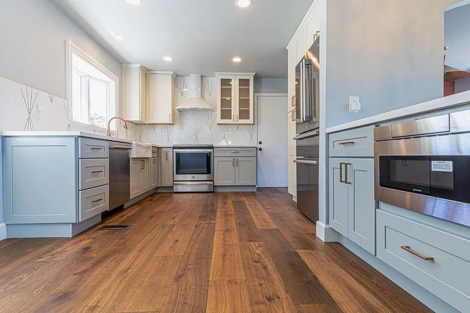U-shaped kitchen with blue-gray shaker cabinets, glass-front uppers, stainless appliances and walnut floors
