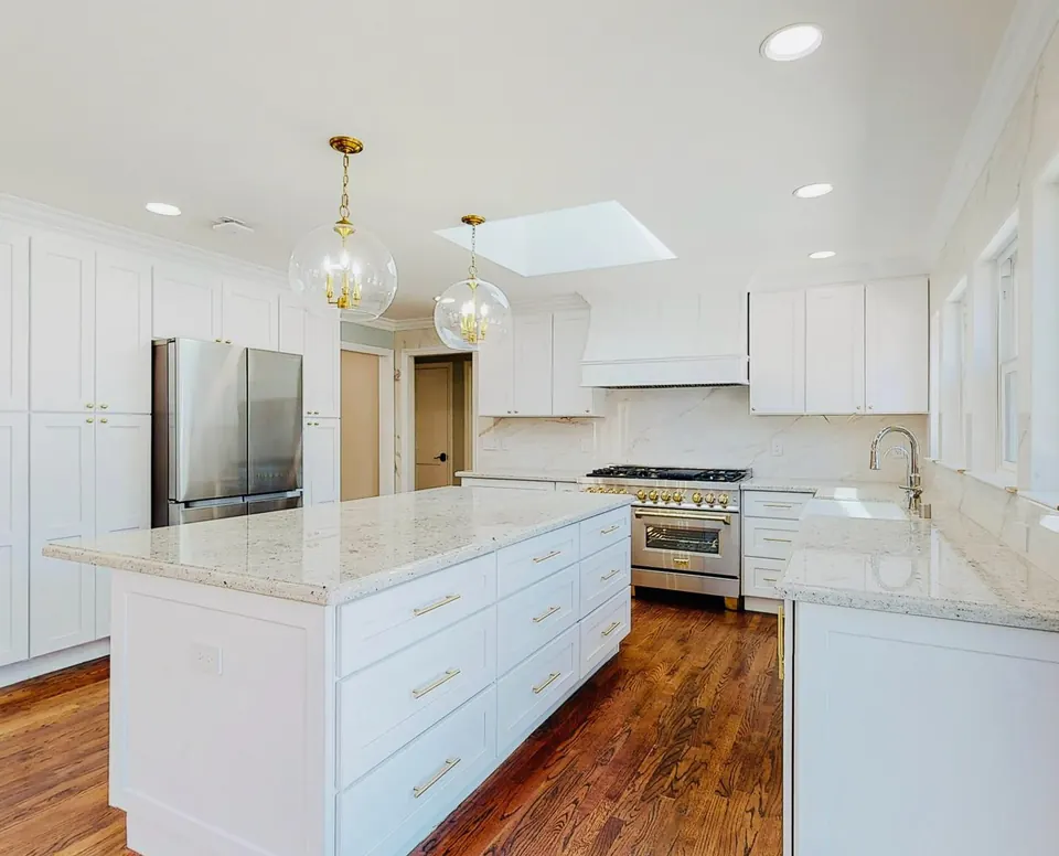 White kitchen with a marble-topped island and brass globe pendants