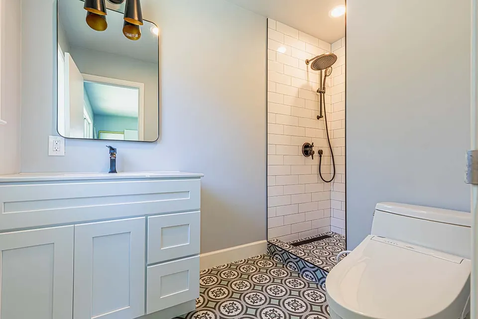 Bathroom with a white shaker vanity, subway-tile shower with matte-black fixtures and a patterned cement-look floor